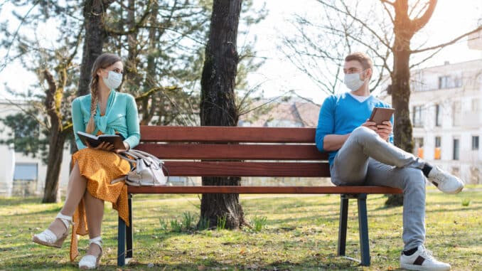 Woman and man in social distancing sitting on bench